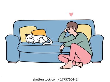 A man is sitting on the floor in the living room and lovingly looking at the cat on the sofa. hand drawn style vector design illustrations. 