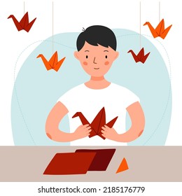 A Man Is Sitting At The Table And Making A Red Crane Out Of Paper. Boy Makes Origami. Vector Flat Illustration.