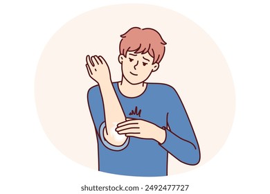 Man smears elbow with healing ointment after bruise or skin problems and acne. Young guy uses analgesic dermatological ointment to treat elbow joint and take care of skin in need of moisture