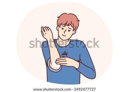 Man smears elbow with healing ointment after bruise or skin problems and acne. Young guy uses analgesic dermatological ointment to treat elbow joint and take care of skin in need of moisture