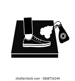 Man standing on disinfection mat to clean shoe from Covid-19 coronavirus and bacteria. Hand holding disinfecting alcohol bottle spraying to clean shoe. Black and white.	