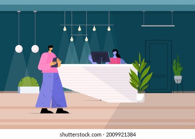 hombre de pie en la recepción y hablando con recepcionista en el hotel o en la oficina a lo largo