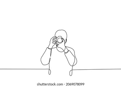 man stands with camera taking pictures of the viewer - one line drawing vector. concept of amateur or professional photographer, journalist reporter 