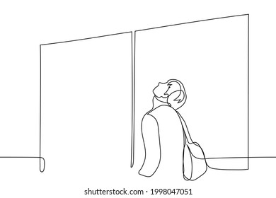 man stands in front of closed doors with a backpack on his back, his face pointing up - one line drawing vector. concept of impatient passenger waiting for boarding start 