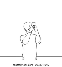 man stands with his mouth open holding a phone in front of him, which takes pictures of what is happening at eye level - one line drawing. vertical video shooting concept 