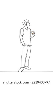 man stands holding a glass of whiskey - one line drawing vector. concept of drinking alone admiring the scenery