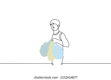 man stands holding three full plastic bags in his hand - one line drawing vector. concept shopper with shopping, plastic pollution