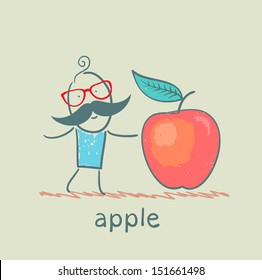 a man stands next to a large apple