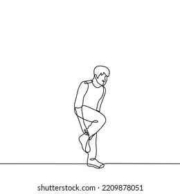 man stands on one leg adjusting his toe on his leg - one line drawing vector. concept to adjust the sock on the go