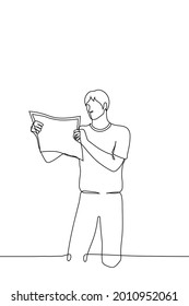 man stands reading a paper newspaper - one line drawing. concept of reading print edition, tourist with paper map of area