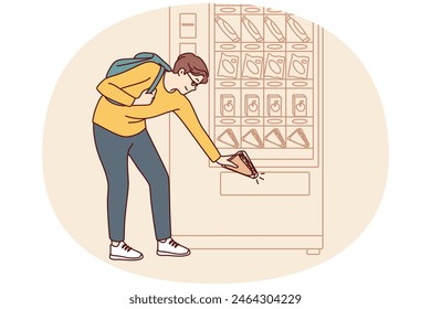 Man student bends down to pick up sandwich while shopping for lunchtime snack from vending machine. Shopper uses automatic vending machine to whet appetite after college or university classes