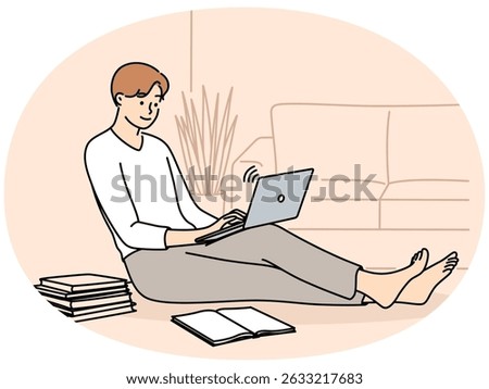 Man student sits on floor with laptop on knees near textbooks and prepares for exam test in college. Guy student receives distance education by studying via Internet