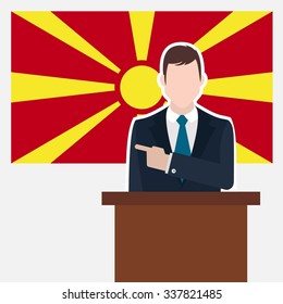 Man in suit standing at rostrum Front of Macedonia Country Flag Pointing to the flag. business man Presentation conference concept. Modern flat design vector background illustration. 

