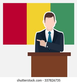 Man in suit standing at rostrum Front of Guinea Country Flag Pointing to the flag. business man Presentation conference concept. Modern flat design vector background illustration.