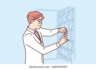 Man system administrator sets up server equipment and connects wires to switches working in hosting company. Guy system administrator is working on connecting high-speed internet in business center