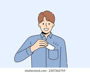 Man takes out business card from pocket to exchange contacts with potential partner or buyer and looks into camera with smile. Business guy in blue shirt wants to share contacts with new acquaintances