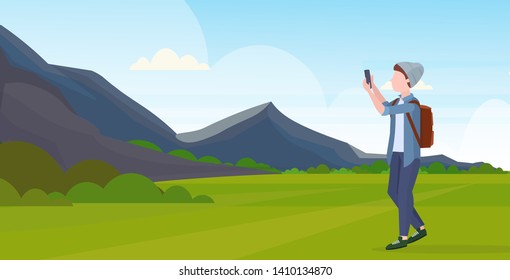 man taking selfie photo on smartphone camera casual male cartoon character in hat with backpack mountains landscape background flat full length horizontal vector illustration