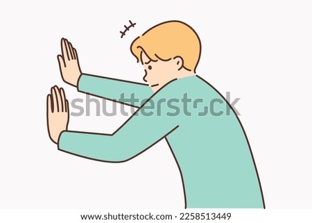 Man tensely pushes invisible wall with hands or sets himself goal of opening secret passage. Metaphor fictitious obstacles on way to achieving goal or inventing non-existent problems on way to dream 