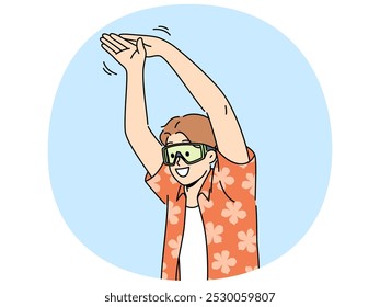 Man tourist stands in pose of swimmer wanting to dive into pool or sea during summer vacation. Young happy guy in goggles for swimming and summer shirt getting ready to jump in sea water