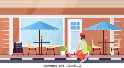 man uniform using paintbrush and paint bucket male cleaner painting sidewalk street service concept modern cafe building exterior flat full length horizontal