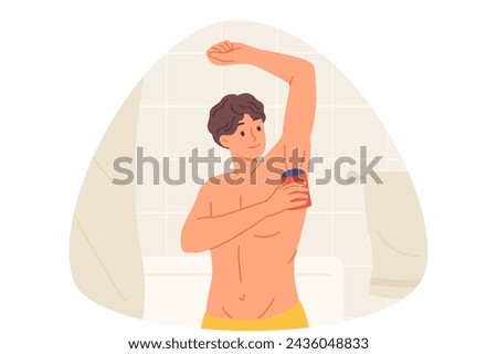 Man uses roll-on deodorant to get rid of sweat on armpits, standing in bathroom with torso naked. Guy gets ready for work or walk in morning, uses deodorant to make good impression on others
