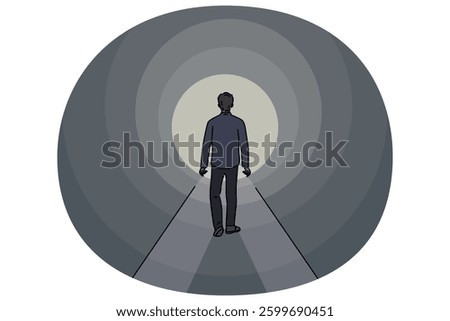 Man walks through dark tunnel towards exit, striving to achieve success and get out of problematic situation. Lonely guy sees light at end of tunnel, walking along mysterious path.