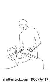 vectores de tracción de una línea. un ama de casa o un mozo lavan una gran sartén mientras se paran frente al fregadero con el grifo en