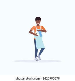 man washing dishes wiping plates with towel on kitchen dishwashing concept african american guy in apron doing housework cleaning concept flat full length