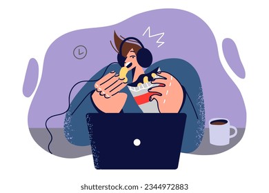 Man watches movie in laptop sitting at table in headphones and eating chips at night. Guy is enjoying new movie blockbuster film shot in hollywood and looks at computer screen intrigued