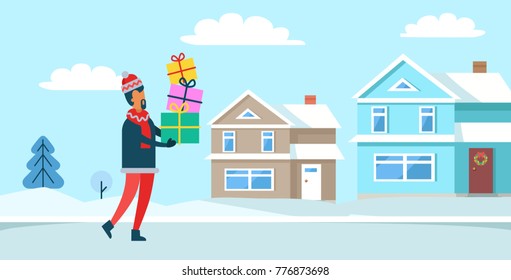 Man wearing warm clothes, standing with presents, tree covered with snow and buildings with wreath as decoration on door vector illustration