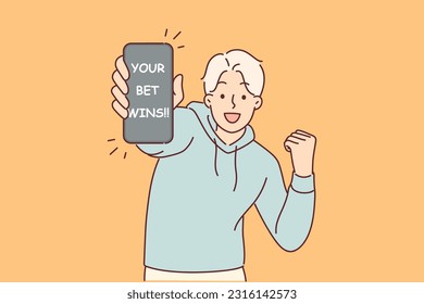 Man wins in online casino or betting application demonstrates mobile phone with message about winning. Guy won jackpot by betting on victory of team in competitions with large odds.