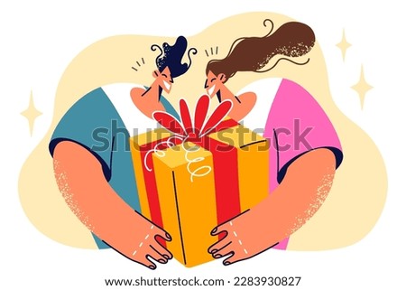 Man and woman with big gift box smiling anticipating emotion of friend who will get birthday present. Young couple received gift in honor of anniversary there since first date or wedding ceremony 