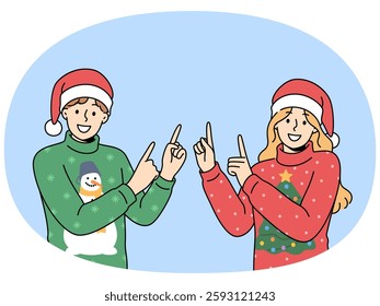 Man and woman in christmas sweaters point fingers upward to visit new year sale. Happy guy and girl in santa hats smiling looking at screen inviting you to christmas party or xmas festival