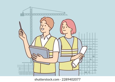 Man and woman in construction uniforms inspect construction site with unfinished high-rise buildings. Builders career concept in engineering or architecture office designing business real estate 