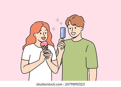 Man and woman eat ice cream to refresh themselves and satisfy hunger during summer walk. Delicious fruit ice cream on stick or in waffle cup in hands of happy teenagers walking around city