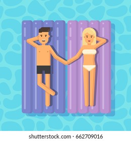 Man and woman floating on mattresses in a swimming pool holding hands