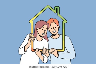 Man and woman with house outline symbolizing family property and sustainable energy efficient housing. Young couple recommends taking out mortgage or insuring house to avoid possible problems