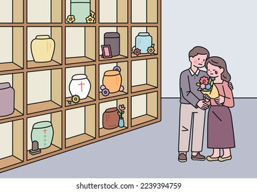 A man and a woman mourn with flowers in a memorial house with a cremation urn.