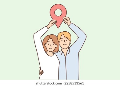 Man and woman stand in embrace and show large geotag to share coordinates for house party or invite friends over. Young couple share geodata on social networks or websites using geotagging