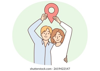 Man and woman stand in embrace and show large geotag to share coordinates for house party or invite friends over. Young couple share geodata on social networks or websites using geotagging