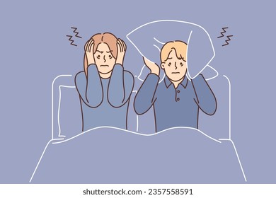 Man and woman suffering from insomnia sit in bed and cover ears with pillow due to noisy neighbors. Married couple cannot sleep because insomnia caused by poor soundproofing in apartment