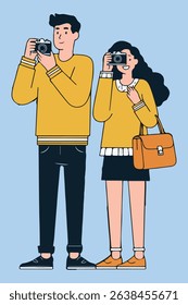A man and a woman are taking pictures with their cameras. The woman has a purse. They are wearing yellow sweaters and dark bottoms.
