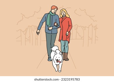 Man and woman are walking their dog together in park enjoying walk on autumn evening with warm weather. Happy couple with white dog on leash take care of pet in need of timely walk outdoors