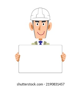 A man in work clothes and a helmet holding a whiteboard