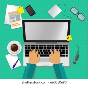 Man working at computer on blue backgroun. Top view. Programmer hands coding.  Programmer typing and using laptop. Coffee cup, telephone paper and glasses around the workplace.  Workspace top view. 