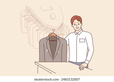 Man working in dry cleaner shows business jacket, cleaned of stains from food or sauce. Dry cleaner manager smiles, inviting to become client and take advantage of services for caring for clothes