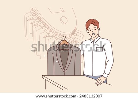 Man working in dry cleaner shows business jacket, cleaned of stains from food or sauce. Dry cleaner manager smiles, inviting to become client and take advantage of services for caring for clothes