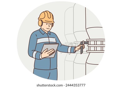 Man working at factory holds electronic tablet standing near industrial equipment and tanks. Employee of industrial company or factory is in boiler room and uses valve to adjust pressure