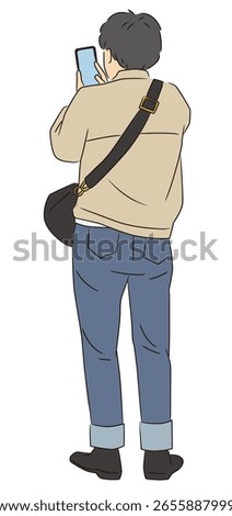 A man's back view looking at his smartphone in the city
