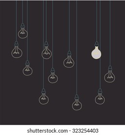 Many unlit lightbulbs with one bulb illuminated